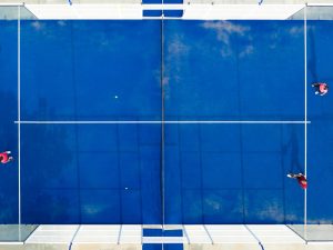 View from above, stunning aerial view of some people playing on a blue padel court. Padel is a mix between Tennis and Squash. It’s usually played in doubles on an enclosed court. מגרשי פאדל בישראל